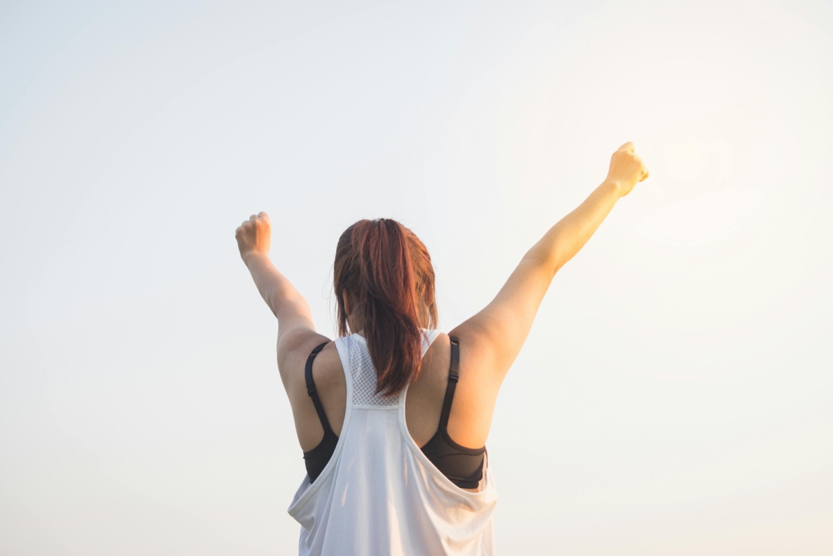 Woman raising her arms outdoors at sunrise